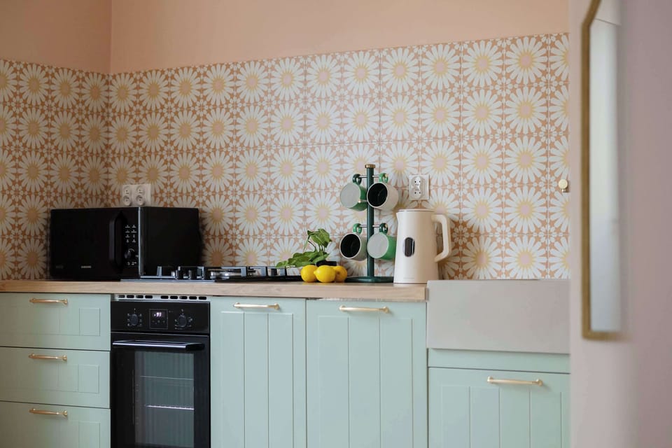 Fully equipped kitchen with pastel cabinetry and modern appliances.