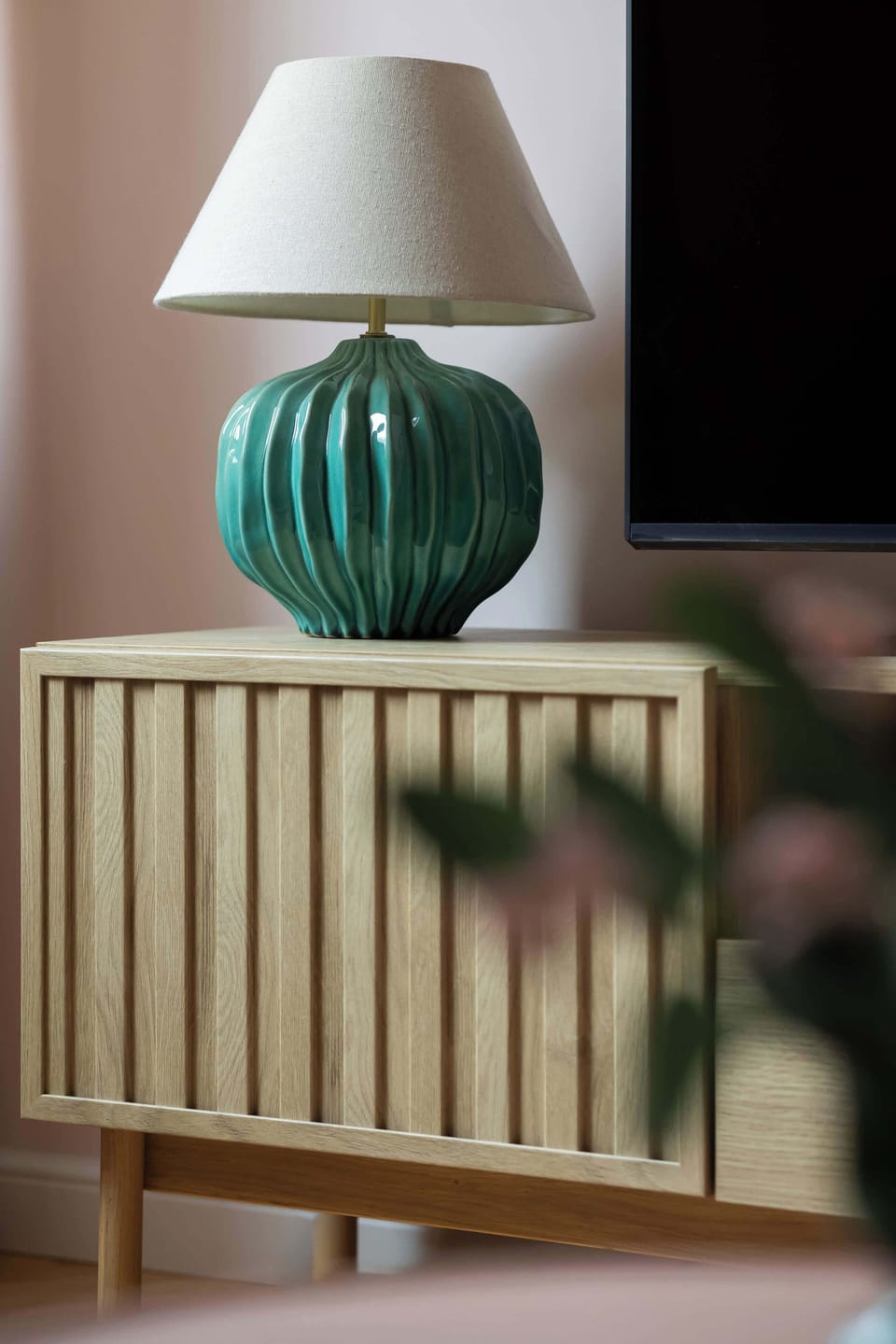 Close-up of a TV cabinet with a television and a charming lamp on top.