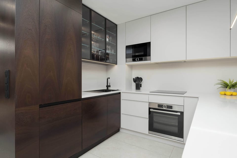 Functional kitchenette with dark wood details and integrated appliances.