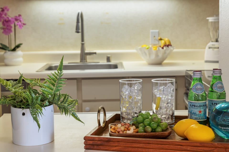 Kitchen counter styled with sparkling water, fresh fruit, and greenery for a welcoming touch.