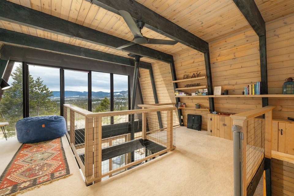 Cozy loft reading nook with stunning mountain views through floor-to-ceiling windows and built-in shelving for your books.