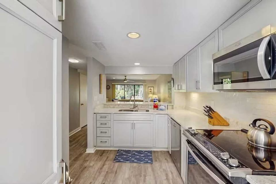 Modern kitchen with stainless steel appliances and white cabinetry overlooking the living area.