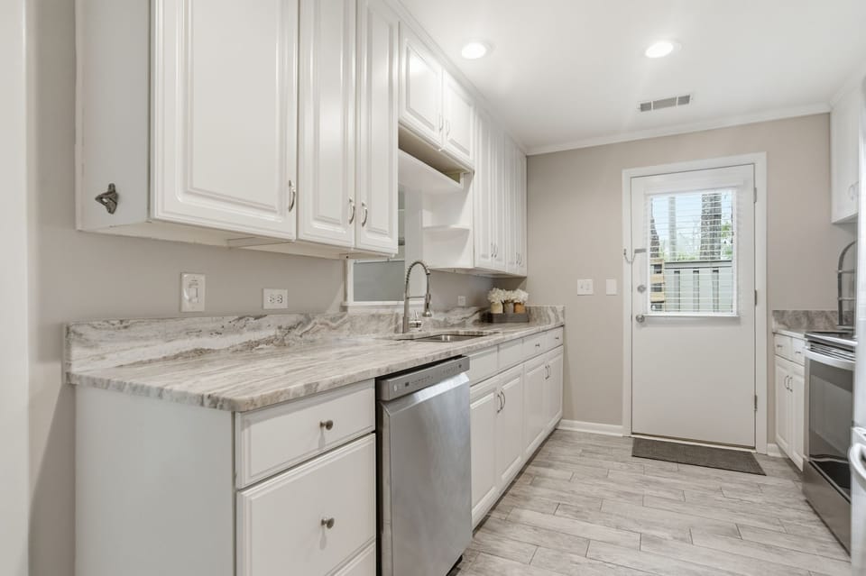Your sleek galley kitchen features marble countertops, crisp white cabinets, and modern appliances—perfect for preparing your favorite meals.