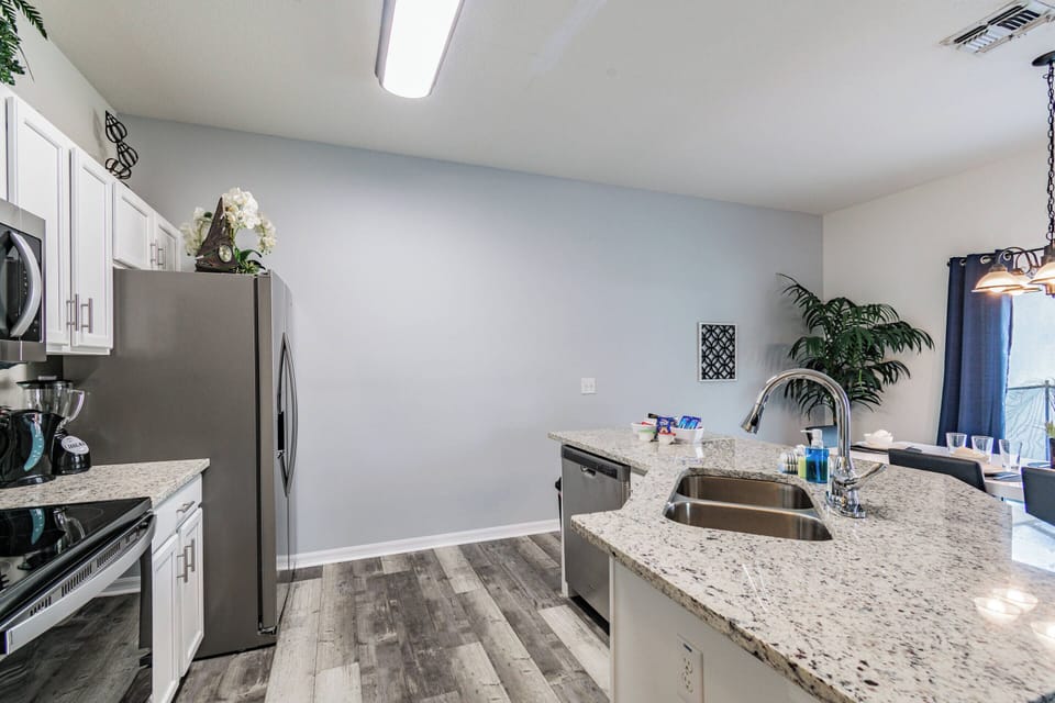 This bright kitchen combines sleek stainless steel appliances with elegant granite countertops, creating a stylish and functional space. The open layout allows for easy movement, and a touch of greenery adds a refreshing vibe.
