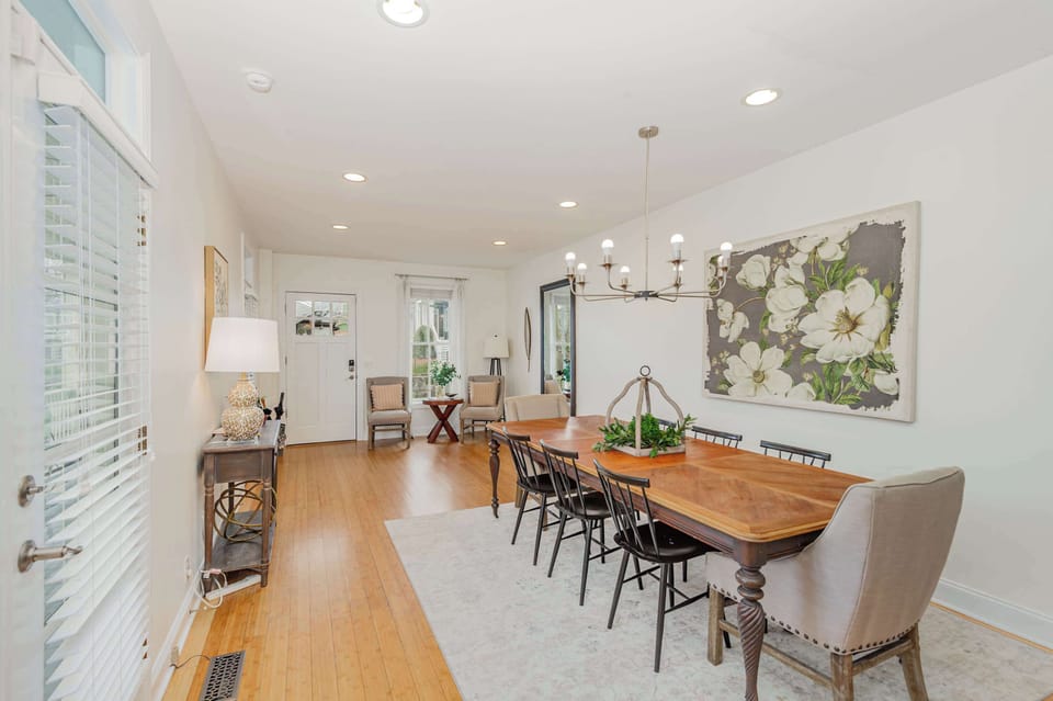 Elegant dining area featuring a large table for eight, modern chandelier, and beautiful artwork.