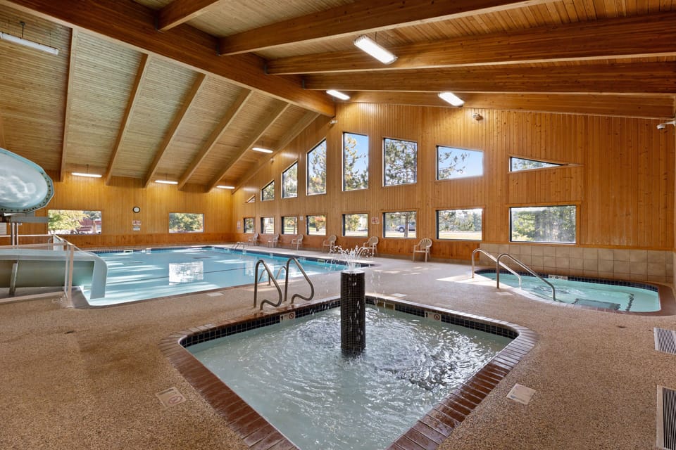 Unwind in the soothing hot tub, nestled in a spacious indoor pool area that showcases stunning views of the wooded surroundings.