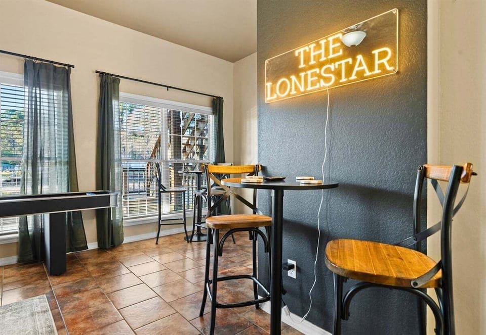 The tall bar table beneath The Lonestar sign creates a cozy spot to enjoy drinks, snacks, or a quick break between games, adding a fun lounge feel to the entire room.