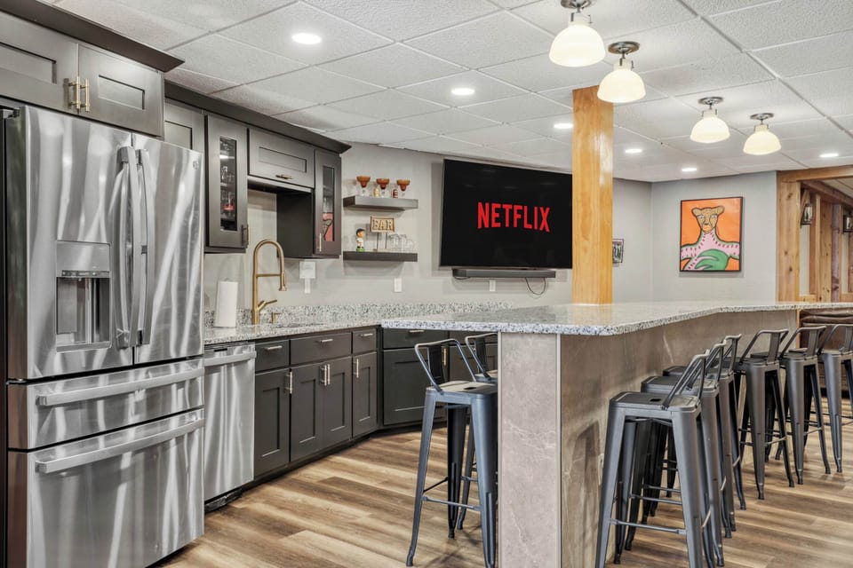 Our lower level is highlighted by a massive wet bar with 12 barstools, perfect for entertaining. We have three 85" smart TV's, 22ft shuffleboard table, darts, large gathering area, 1/2 bathroom, and walk out access to the exterior amenities.