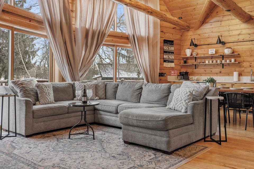 Our luxury log cabin living room features a large sectional, 65" smart TV, gas fire place, walkout access to the front deck, and an open concept into the dining and kitchen area. We have dining seats for 18.