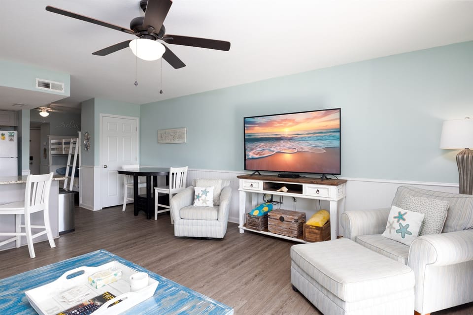 Open-concept living area with comfy seating and a large Smart TV