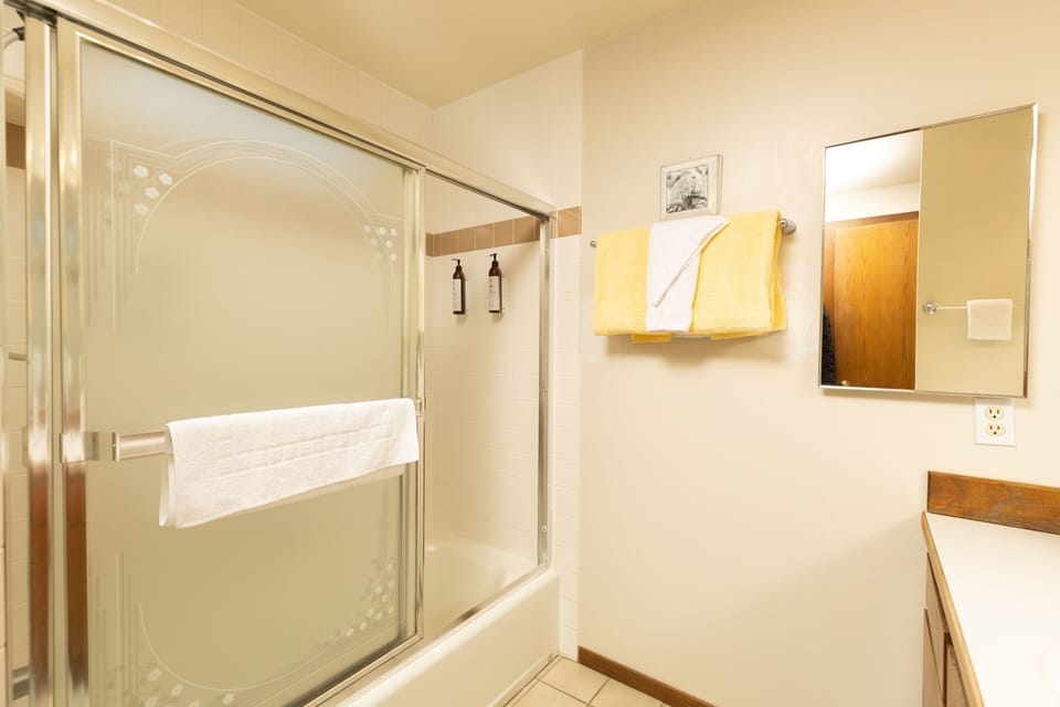 A bathroom featuring a shower and tub combination with sliding glass doors.