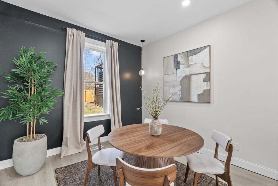A round four-seat table, statement wall, artwork, and greenery create an inviting dining space.