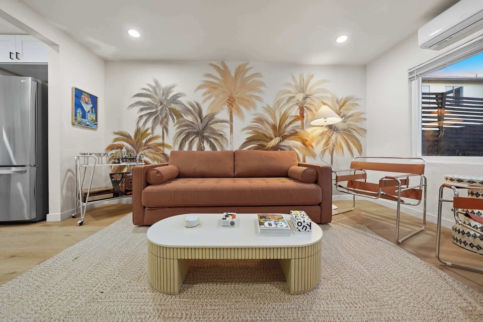 Spacious living area with palm mural and natural light.