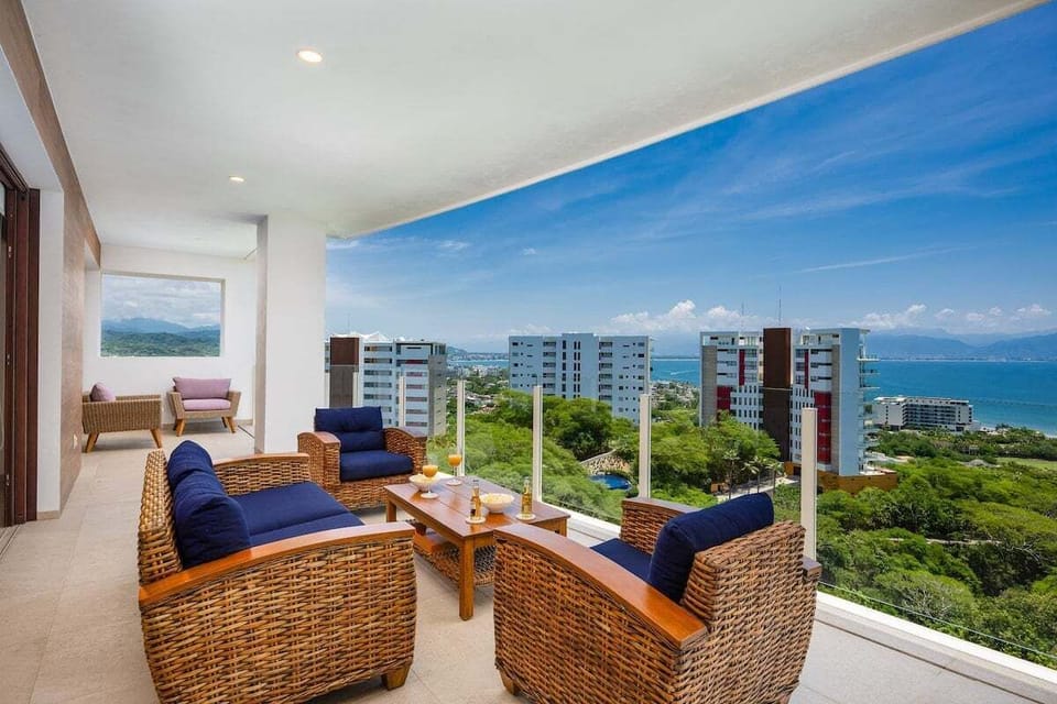 Showcases a spacious outdoor living area furnished with wicker sofas and blue cushions.