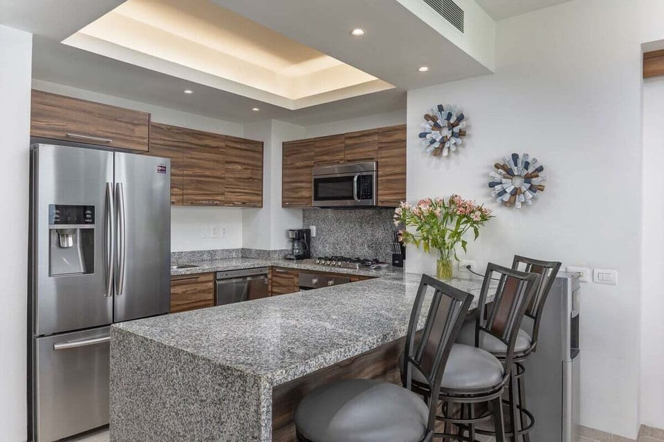 Highlights a sleek kitchen with granite countertops, stainless steel appliances, and wood-grain cabinetry.