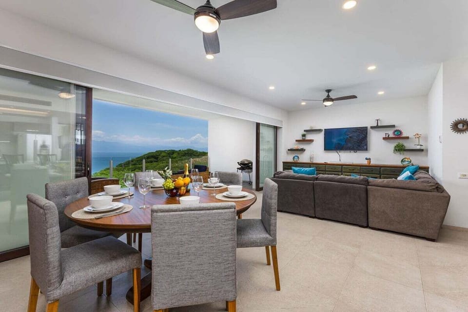 Features a dark wood circular dining table positioned to take advantage of the ocean breeze.