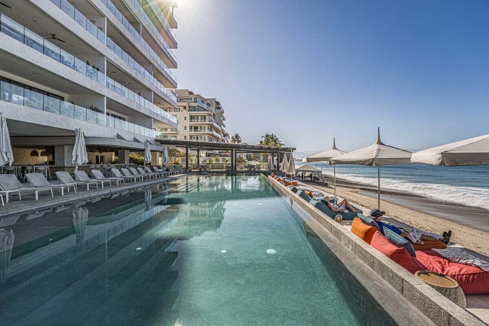 Enjoy the resort's beachfront infinity pool with sun loungers, shaded seating, and direct access to the sandy shores of Puerto Vallarta.