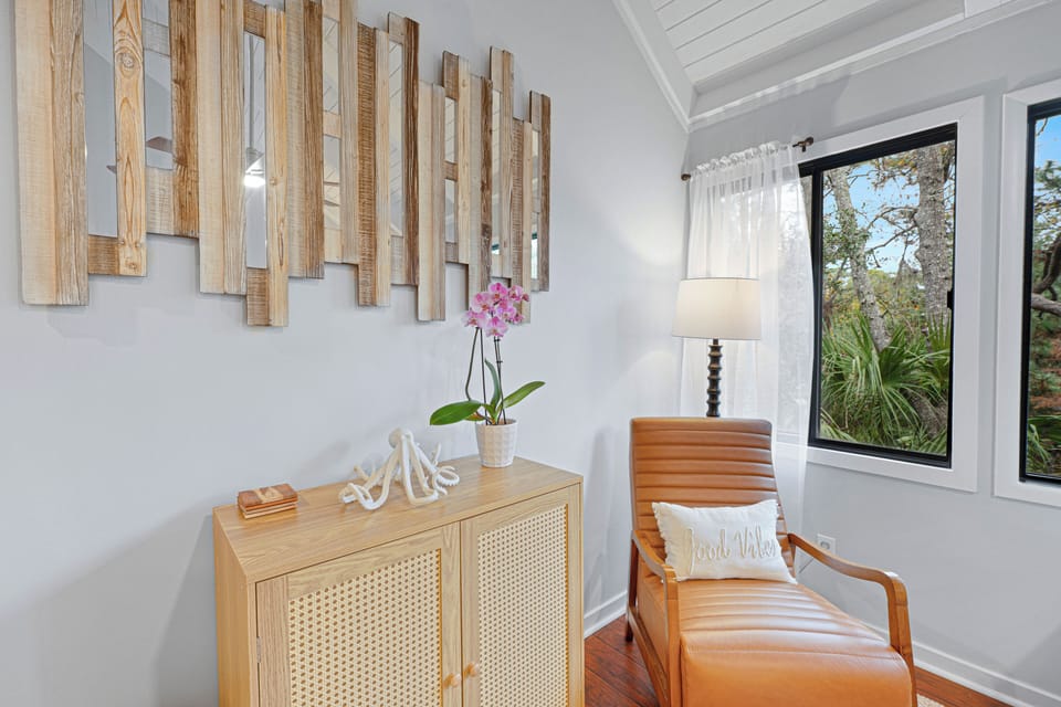 This inviting reading nook offers a bright, tranquil corner to unwind, featuring large windows with peaceful Lowcountry views.