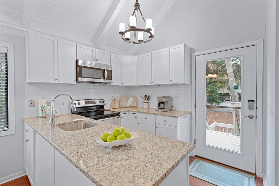 This bright, updated kitchen features white shaker cabinets, granite countertops, stainless steel appliances, and a clean subway tile backsplash.