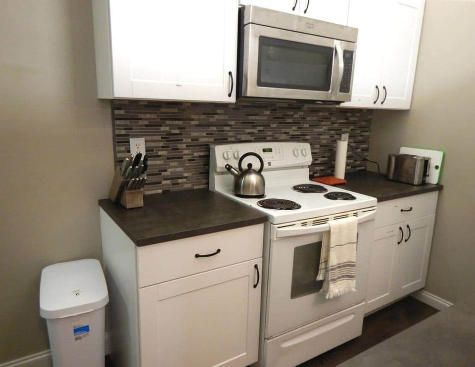 This is the left half of the kitchen.  Stove, microwave, with toaster and knife set on the counter.  Pots and pans are stored in the cupboard down and to the right.