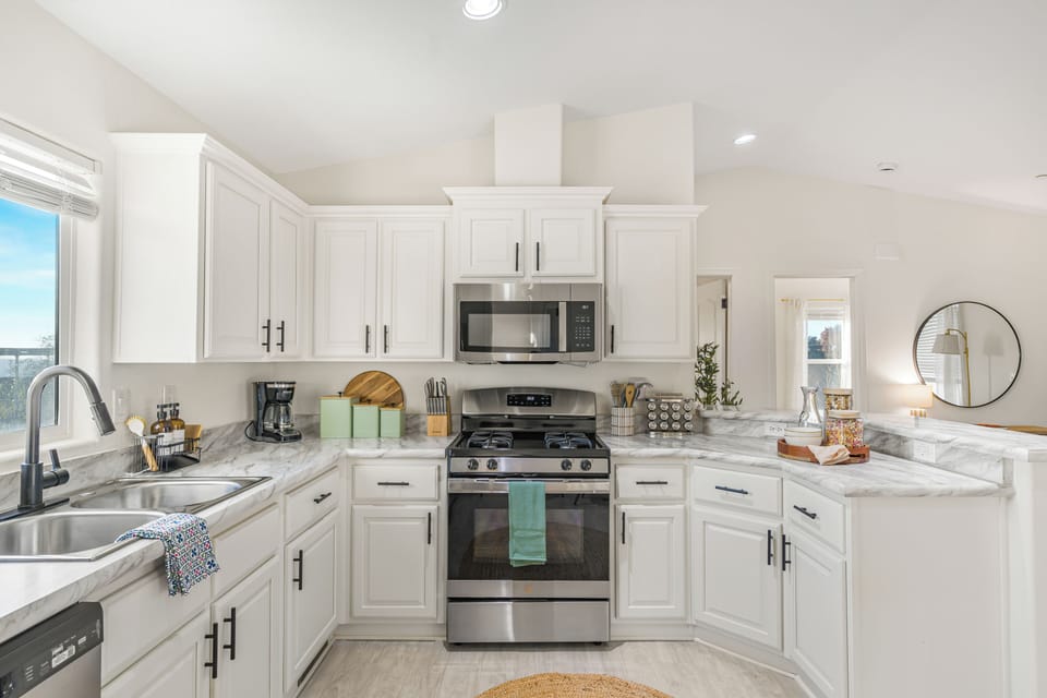 White kitchen with shaker cabinets, stainless steel appliances, and a gas stove.