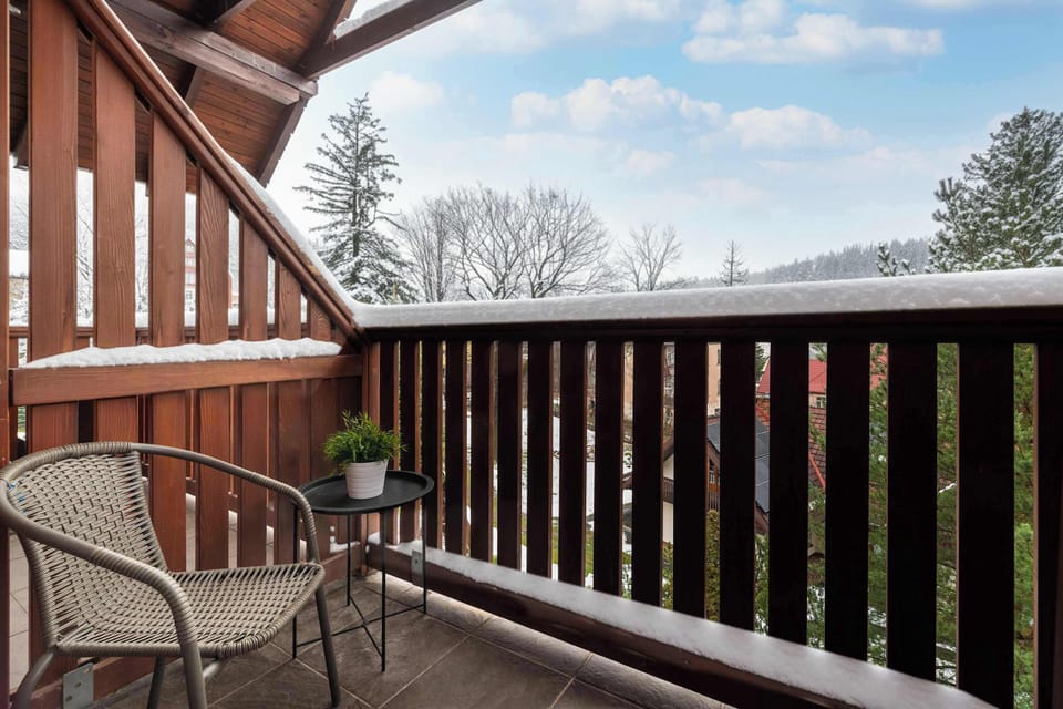 Spacious balcony with charming wooden railings and relaxing outdoor seating.