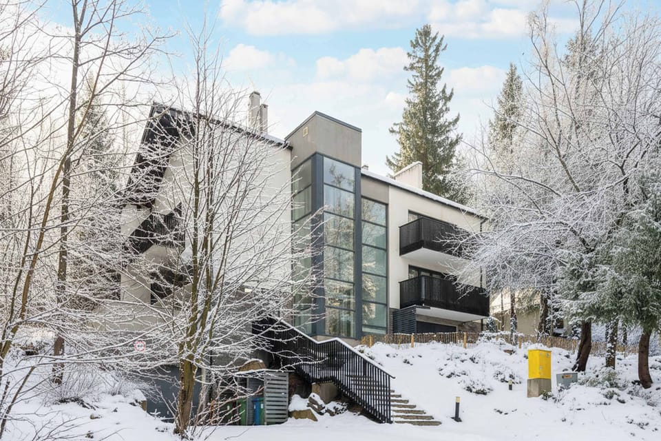 The exterior of the building shows the studio’s access to a peaceful garden and terrace. Snow-covered trees create a calm and inviting atmosphere around the property.