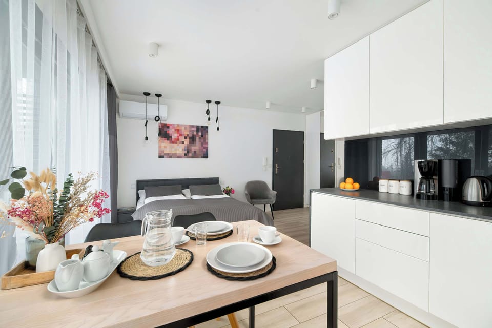 The dining corner beside the kitchenette is neatly arranged with plates and flowers. It creates a warm and intimate space for meals within the studio.