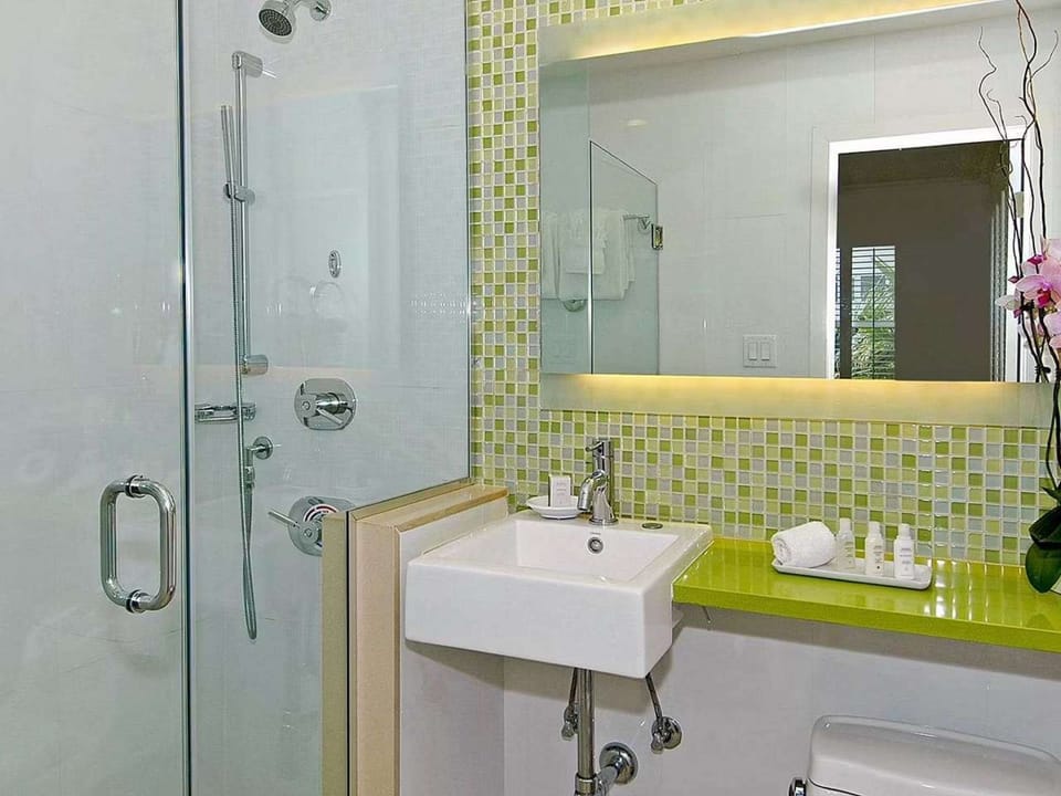 Bright bathroom with green tile, glass shower and lit mirror