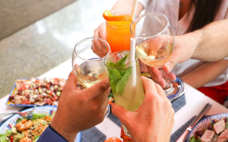 Guests clinking glasses over fresh drinks and tasty dishes