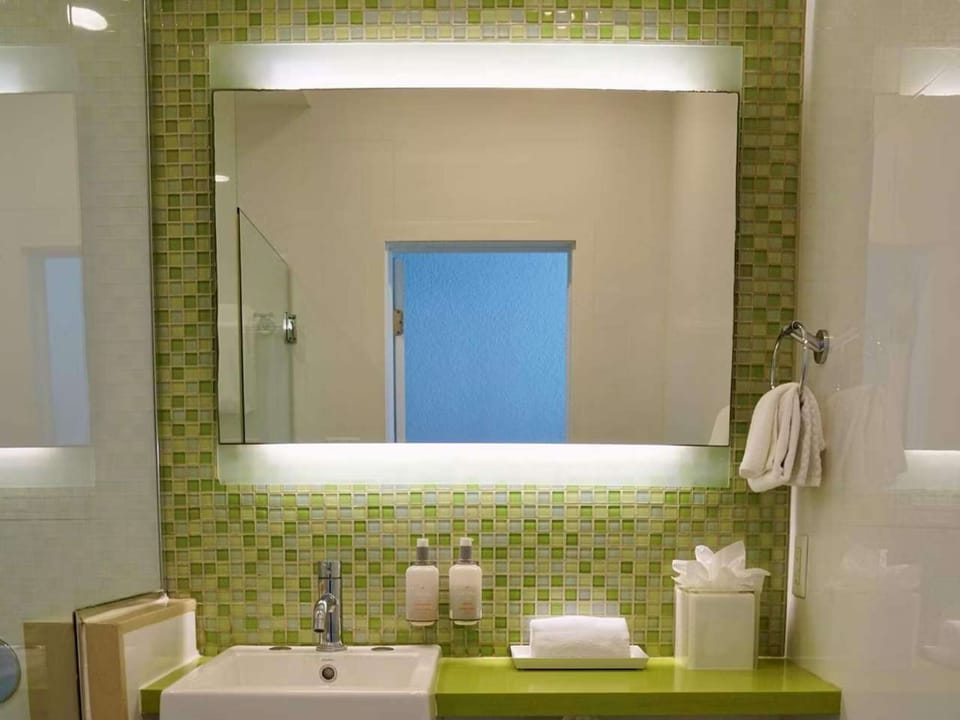 Clean bathroom with green tile wall, bright sink and soft towels
