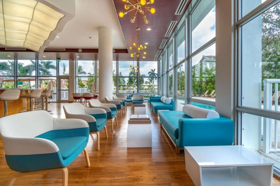 Indoor seating area with blue chairs and big windows by the pool