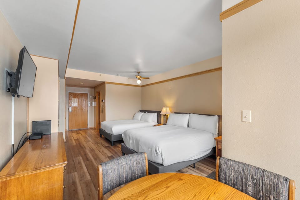 Relax in your spacious room with two queen beds, modern furnishings, and entertainment options for a comfortable stay.