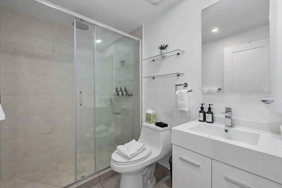 Your spotless bathroom features a modern glass-enclosed shower, sleek vanity, and thoughtful amenities, making your morning routine feel like a spa experience.