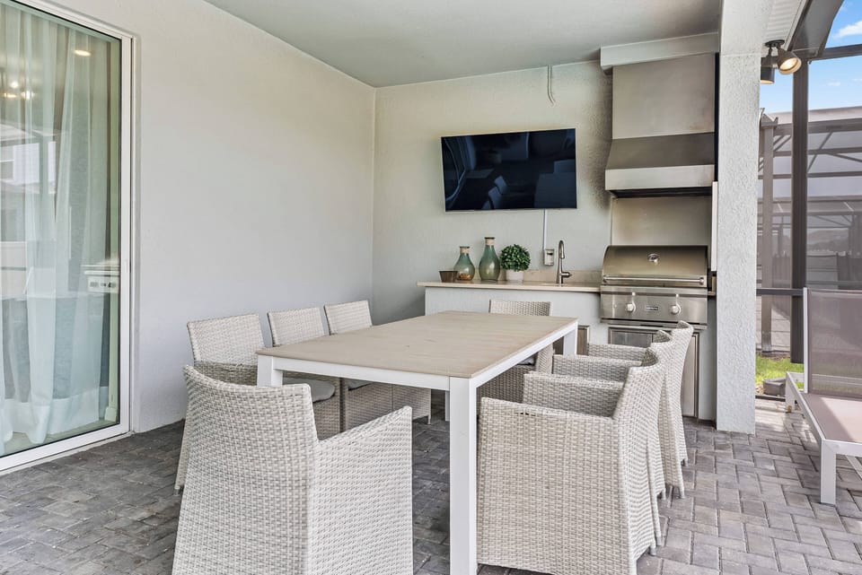 Enjoy our spacious outdoor dining area, featuring a sleek white table and cozy wicker chairs, ideal for gatherings. With a built-in grill and modern TV, you can savor meals and entertainment while basking in the fresh air.