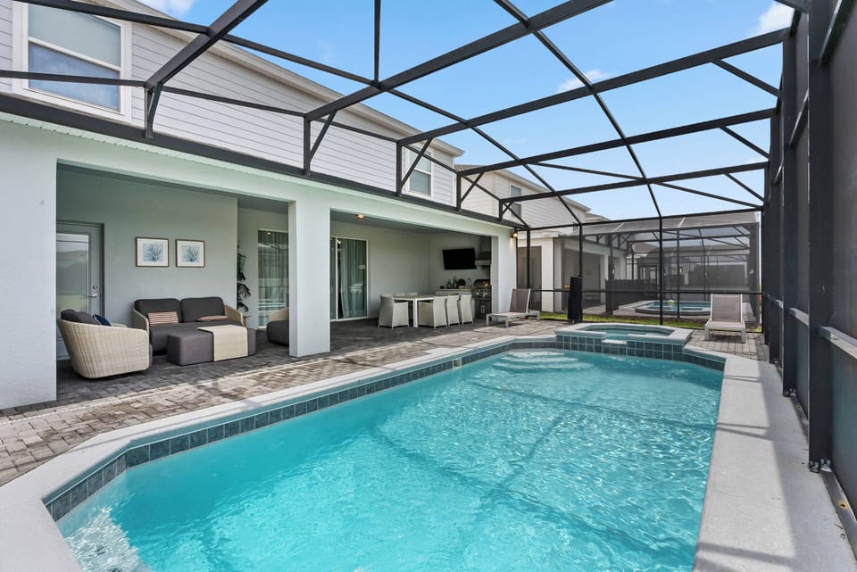 Discover your private oasis with a sparkling pool in a screened enclosure, blending indoor and outdoor living. Unwind on chic lounge chairs or savor a meal in the sunlit dining area, creating a perfect retreat for relaxation.
