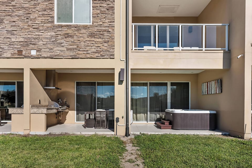 Step outside to your private patio with a luxurious hot tub, ideal for stargazing. The chic stone accent wall and modern outdoor furniture create a relaxing atmosphere that invites you to unwind and enjoy your time.