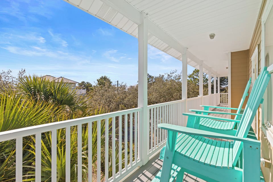 Relax in your bright turquoise chairs on this covered balcony, where tropical palms frame peaceful views of the neighborhood.