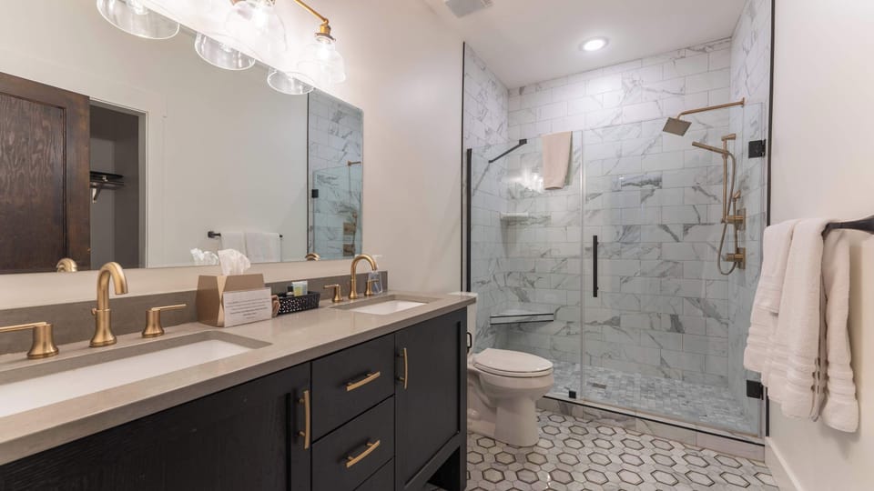 Comfortable bedroom featuring plush bedding, bedside lighting, stylish furnishings, and large windows that bring natural light into this welcoming guest retreat.