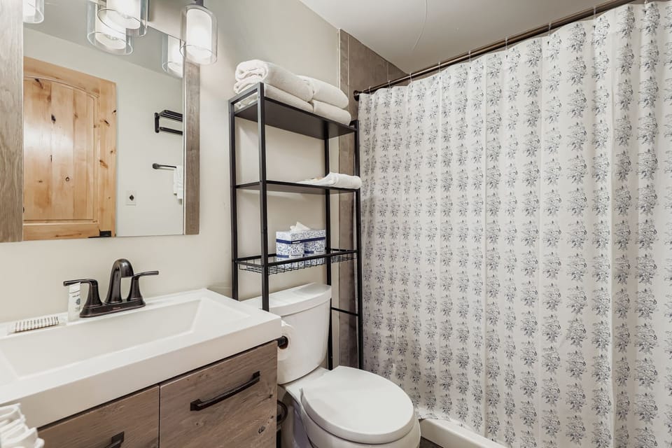 Refresh in your stylish bathroom featuring a modern vanity, rainfall shower, and thoughtful storage for all your essentials during your stay.