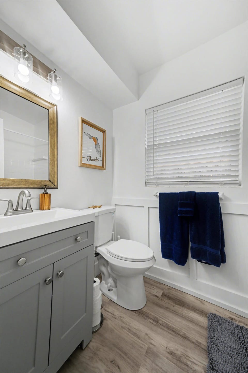 Freshen up in this bright, spotless bathroom with modern fixtures, wood-look flooring, and coastal touches—soft towels and a clean tub ready for your stay.