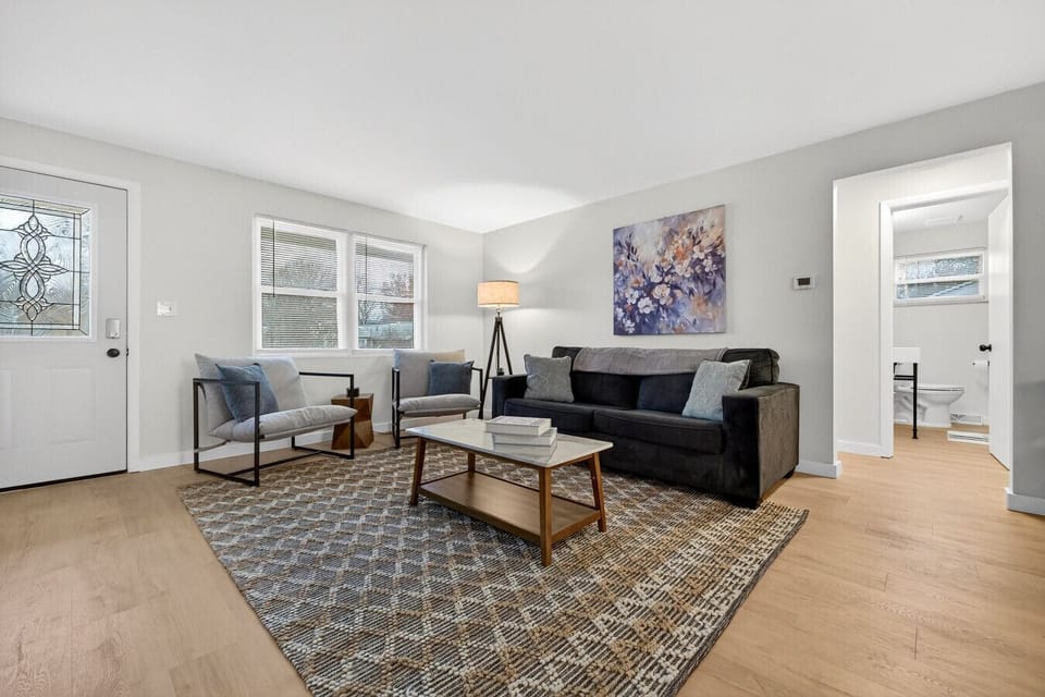 Living room with sleeper sofa, two armchairs, Smart TV, and large windows.