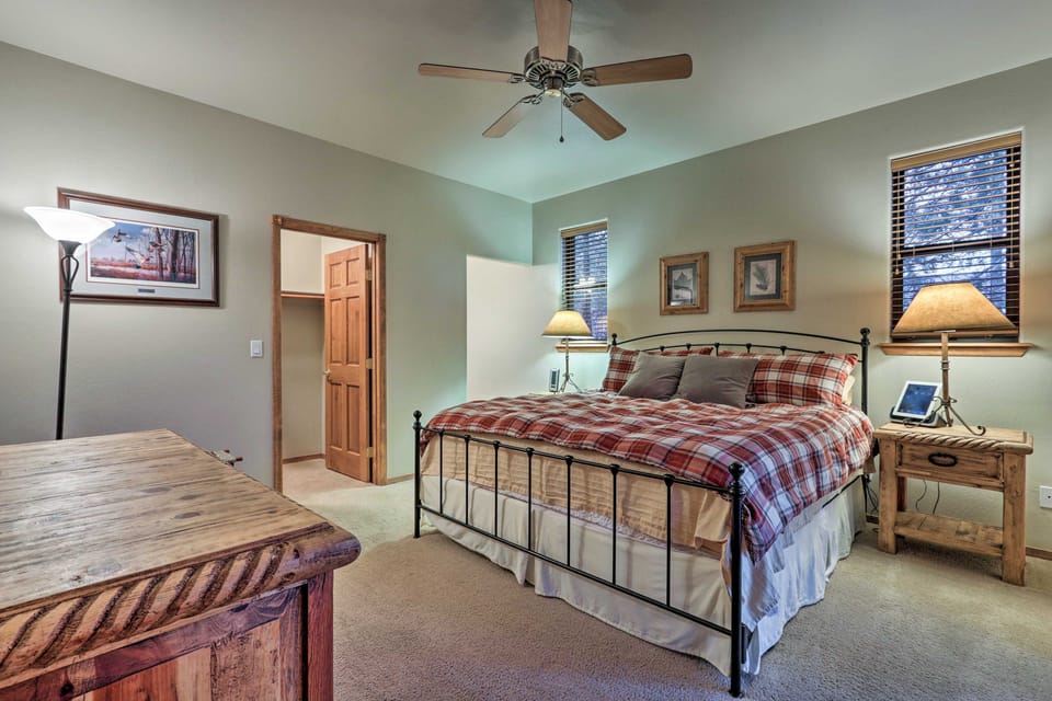 A bedroom furnished with a black metal bed, rustic wood accents, and soft carpet.
