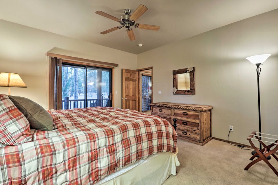 Bedroom with plaid bedding, a rustic dresser, and sliding doors to the deck.