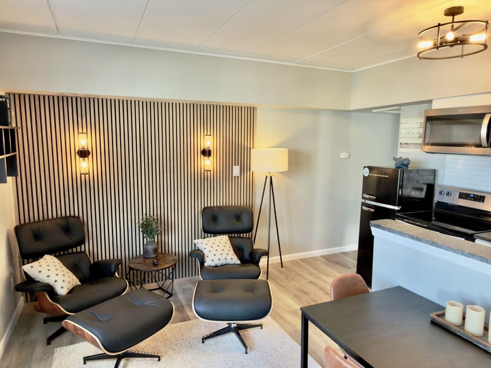 Spacious living room view showcasing comfortable seating, warm wooden floors, modern furniture, stylish decor and abundant natural light, creating a welcoming environment for you.