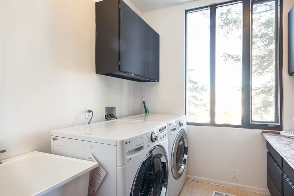 Laundry with mountain view, dryer, washer, folding table. 