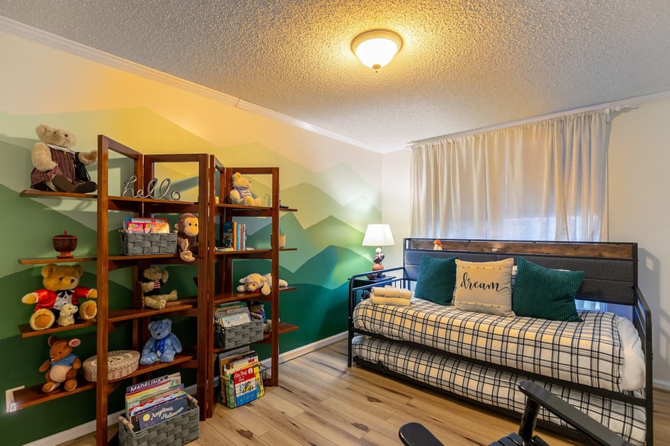 Little ones will love the mountain-mural bedroom at Our Happy Nest, complete with a cozy daybed and shelves full of books and stuffed animals.