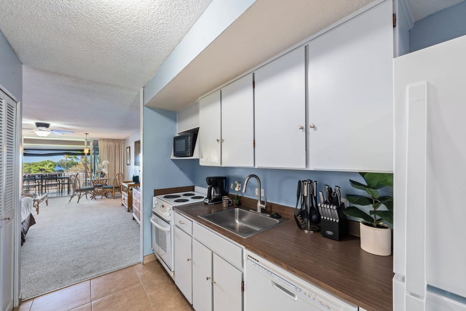 Cook with ease in the bright kitchen featuring white cabinets, full appliances, and tropical charm