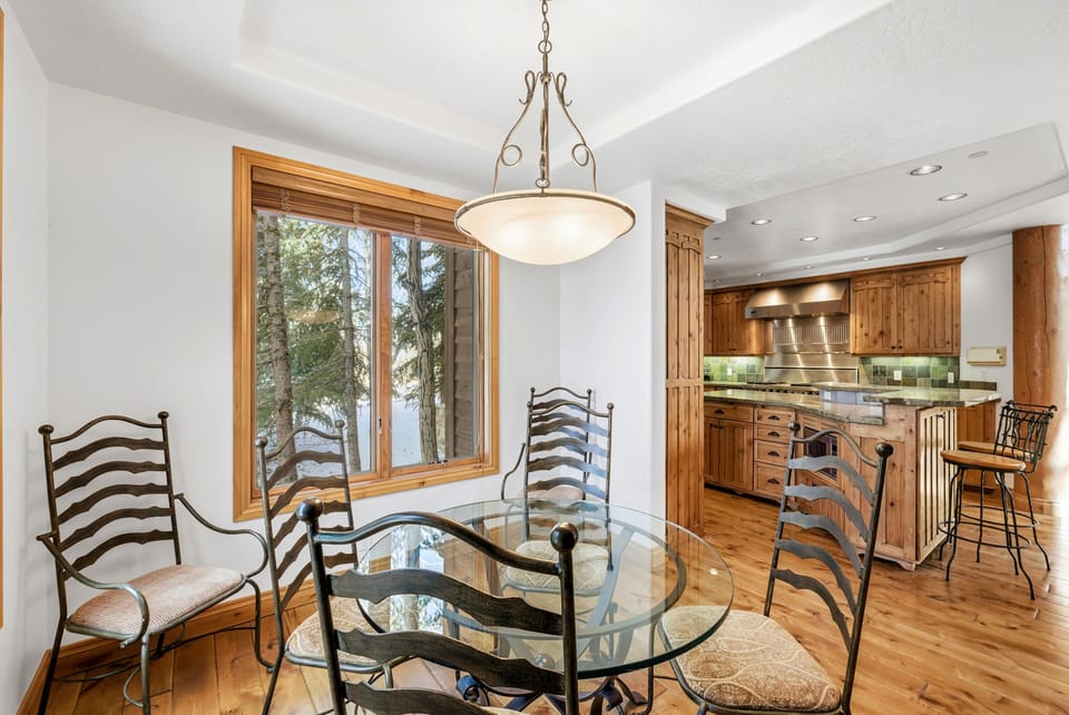 Bright breakfast nook with circular table and high-top chairs, opening into a spacious kitchen with bar seating and wood cabinetry.