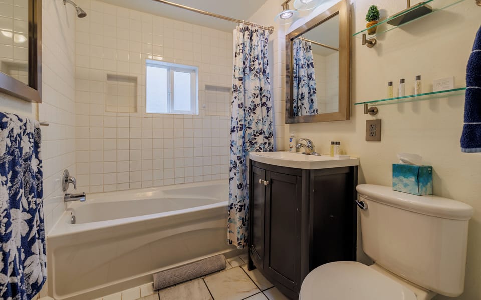 The bright full bathroom features a tub and shower combo.